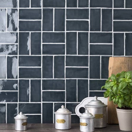 Wall of metro dark navy blue handmade wall tiles behind a grey wood work top and kitchen pots