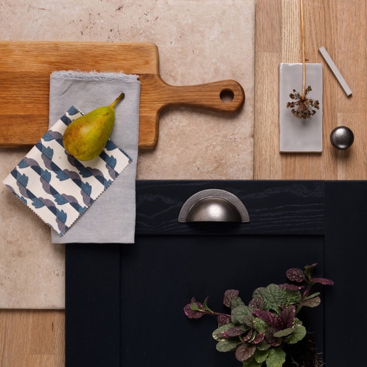 Flatlay of oak effect plank with navy cupboard doors, a grey tile and stone floor tile