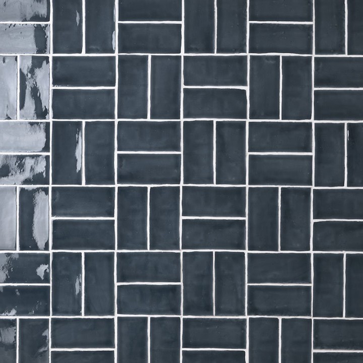 Wall of metro dark navy blue handmade wall tiles behind a grey wood work top and vases