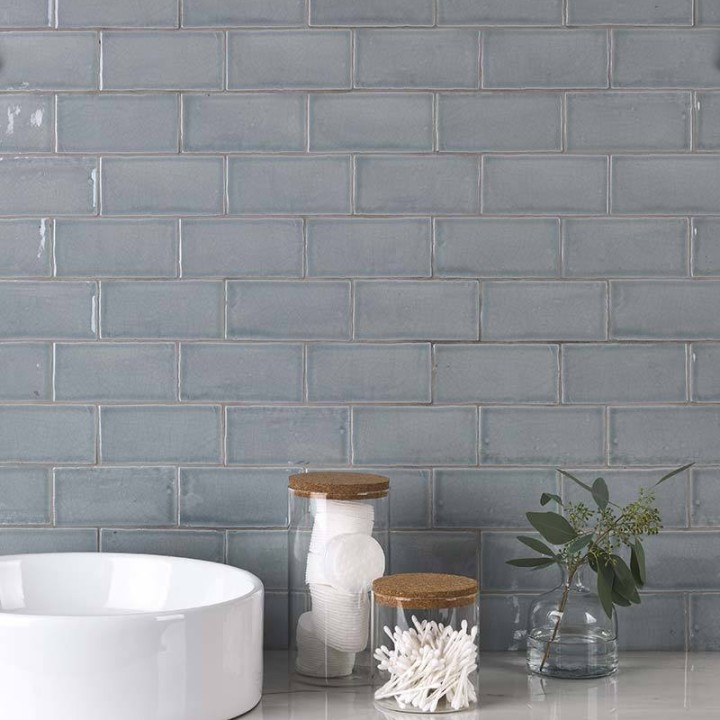 Wall of metro medium grey handmade wall tiles behind a marble work top and bathroom accessories