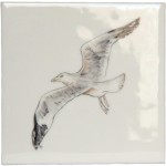 A cut out of an antique white square tile with seagull illustration