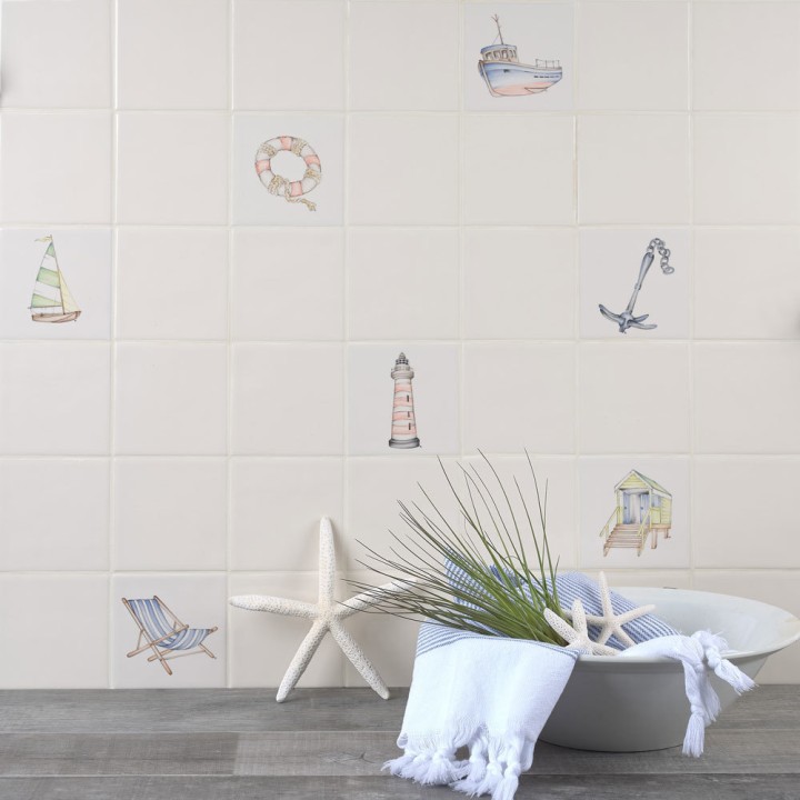 Wall of antique white square tiles with seaside illustrations like deck chairs, beach huts and boats behind coastal accessories