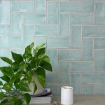 Wall of gloss cool blue medium metro tile laid in a vertical herringbone tile pattern behind a pothos