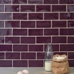 Wall of gloss plum purple medium metro tile laid in a brick bond tile pattern behind kitchen accessories