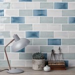 Wall of mix of blue, green and neutral medium metro tiles laid in a brick bond tile pattern behind office accessories