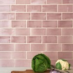 Wall of gloss dusky rose pink medium metro tile laid in a brick bond tile pattern behind kitchenware