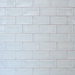 Wall of gloss neutral cool white metro tile laid in a brick bond tile pattern finished with silver grey grout