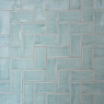 Wall of gloss cool blue medium metro tile laid in a vertical herringbone tile pattern finished with beige grout