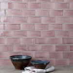 Wall of gloss dusky rose pink medium metro tile laid in a herringbone tile pattern behind home accessories