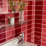 Wall of deep burgundy and red metro tiles in a gradient affect behind a traditional sink and glass shelf