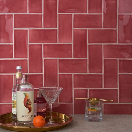 Wall of gloss bright red medium metro tile laid in a herringbone tile pattern