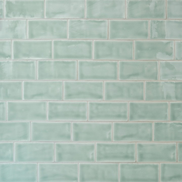 Wall of gloss cool blue green medium metro tile laid in a brick bond tile pattern finished with silver grey grout