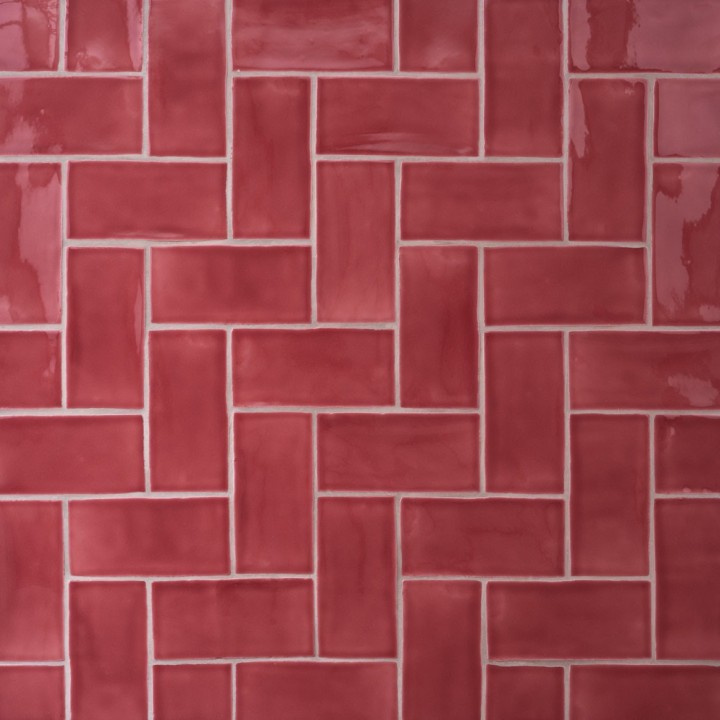 Wall of gloss bright red medium metro tile laid in a herringbone tile pattern
