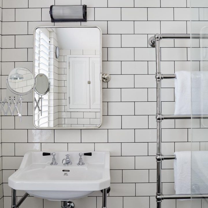 Utilitarian bathroom with chrome fixtures and a wall of matt white medium metro tiles