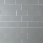 Wall of green toned grey large metro brick tiles laid in a brick bond pattern