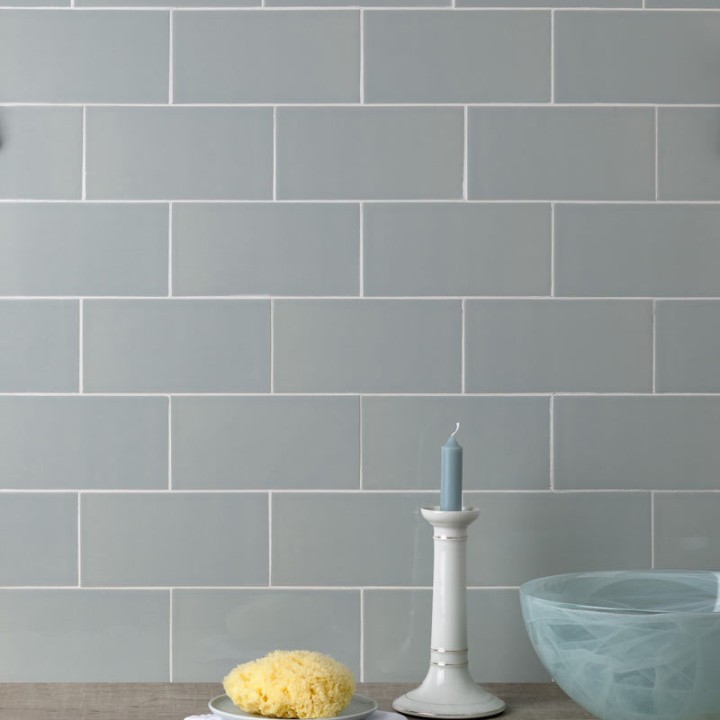 Wall of green toned grey large metro brick tiles laid in a brick bond pattern against an oak work top