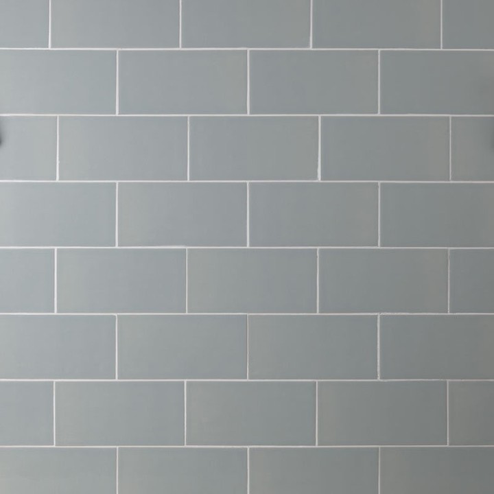 Wall of green toned grey large metro brick tiles laid in a brick bond pattern