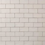 Wall of warm white medium brick metro tiles with beige grout laid in a brick bond tile pattern