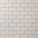 Wall of warm white medium brick metro tiles with beige grout laid in a brick bond tile pattern