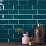 Wall of sapphire navy blue medium brick metro tiles with white grout against a grey wood worktop with home accessories on top