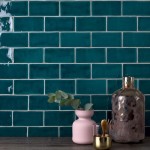 Wall of sapphire navy blue medium brick metro tiles with white grout against a grey wood worktop with home accessories on top