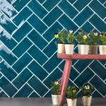 Wall of teal medium brick metro tiles with white grout against a stone worktop with home accessories in front