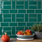 Wall of bottle green medium brick metro tiles with white grout against an oak worktop with kitchen accessories on top