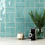 Wall of aqua green medium brick metro tiles with beige grout against a stone worktop with kitchen accessories on top