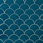 Wall of teal scallop tiles with white grout laid in a fish scale pattern ideal for kitchens and bathrooms