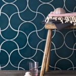 Wall of navy blue scallop tiles with white grout against an oak porcelain floor behind a stool