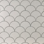 Wall of warm white scallop tiles with medium grey grout laid in a fish scale pattern ideal for kitchens and bathrooms