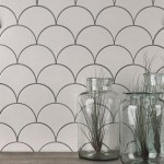 Wall of warm white scallop tiles with medium grey grout against an oak work top behind some vases