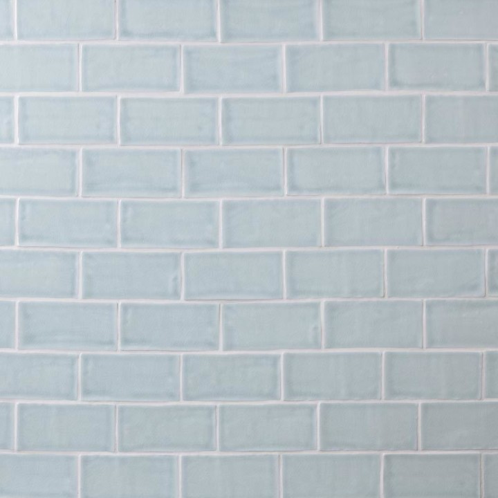 Wall of pale blue medium brick metro tiles with silver grey grout laid in a brick bond tile pattern