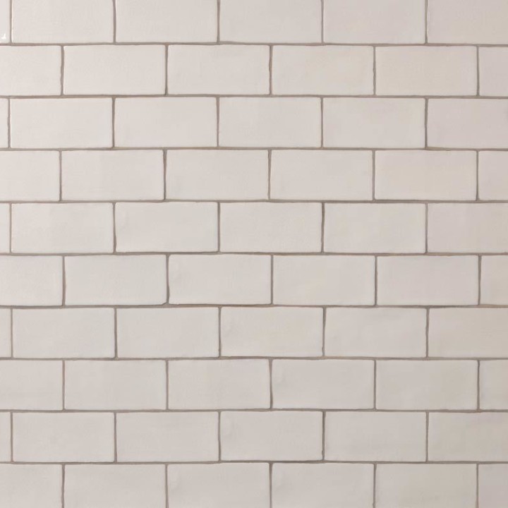 Wall of warm white medium brick metro tiles with beige grout laid in a brick bond tile pattern