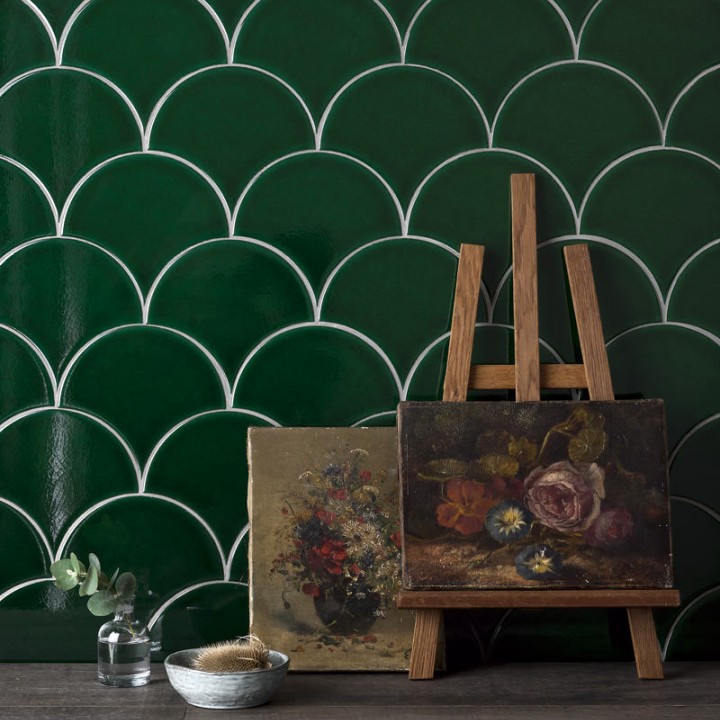 Wall of emerald green scallop tiles behind an easel with fine art painting