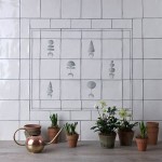 Wall of antique white square tiles with topiary illustrations in a charcoal style framed with charcoal lines