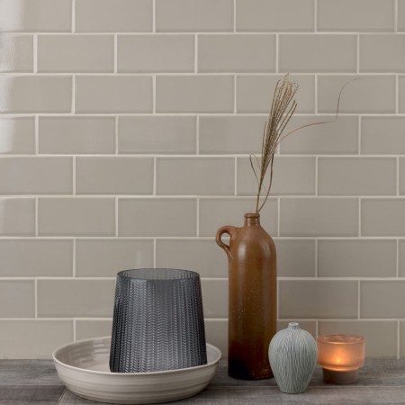 Wall of neutral green toned off white crackle glaze metro tile finished with jasmine grout behind home accessories