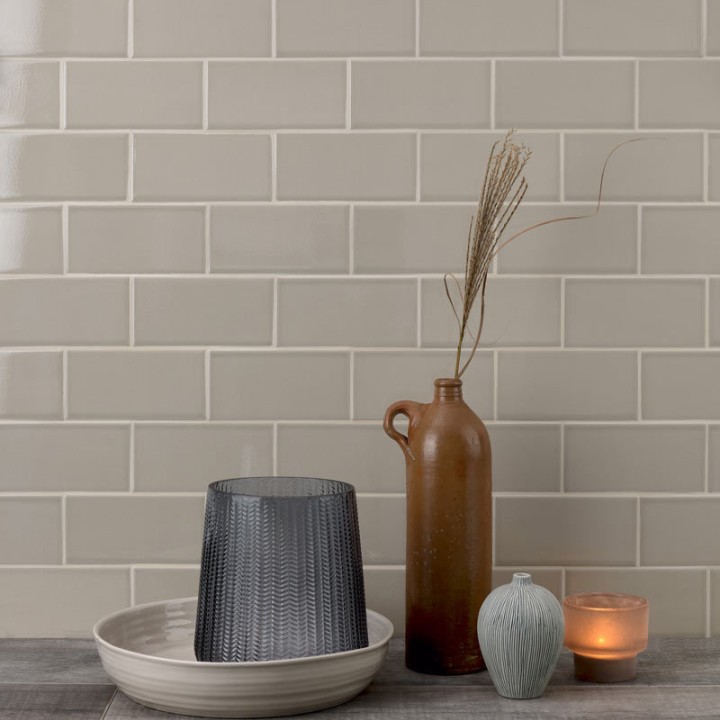 Wall of neutral green toned off white crackle glaze metro tile finished with jasmine grout behind home accessories