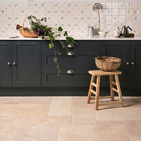 Kitchen with black cabinets featuring a wall of delft wilding tiles with hand painted animal illustrations and limestone floor