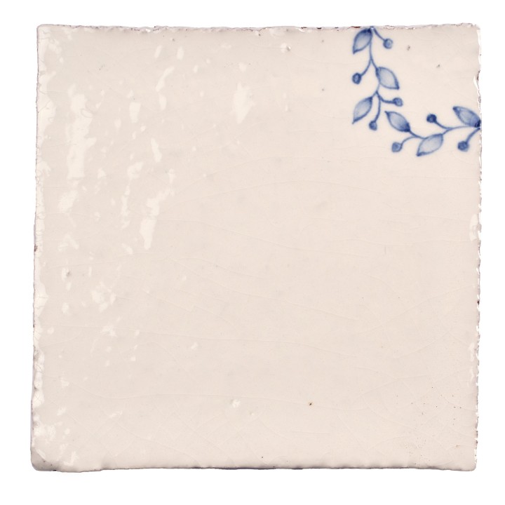 Cut out image of white tile with handpainted delft blue corner pattern