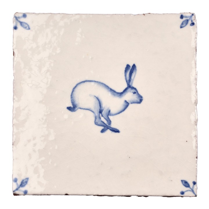 Cut out image of white tile with handpainted delft hare illustration and ornate corners