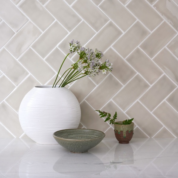 Vase with flowers against delicate grey-green medium brick tiles