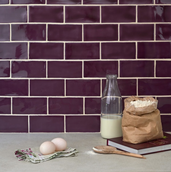A kitchen sideboard with eggs and milk and deep purple medium brick tiles