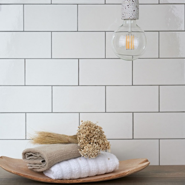 A bathroom shelf with large white brick tiles