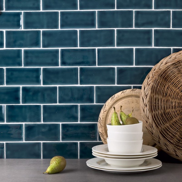 Dinner plates and bowls with pears against a wall of dark blue medium brick tiles