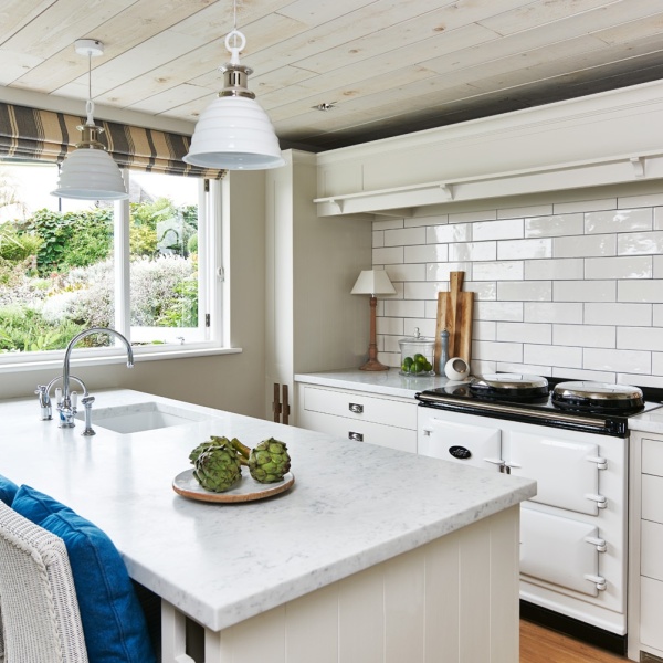 A white kitchen with long brick tiles above a range cooker