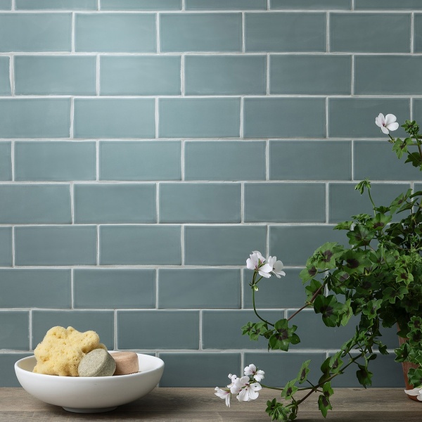 Wall of teal blue green matt metro tile with a house plant and home decor styling