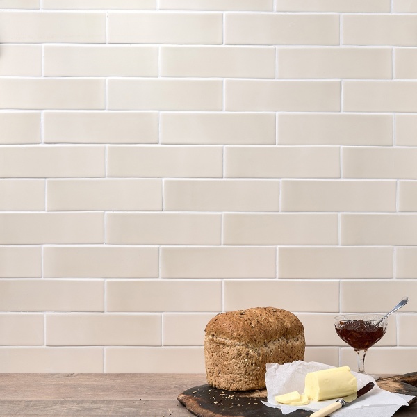 Wall of skinny neutral warm white matt metro tiles with white grout styled with a bread board