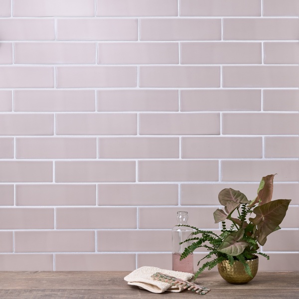 Wall of skinny metro blush pink matt tiles with white grout styled with a house plant