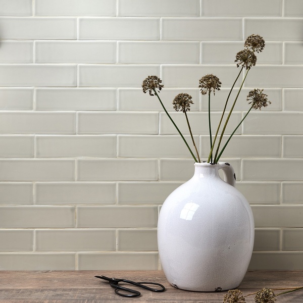 Wall of sage green skinny metro matt tiles with jasmine grout styled with a large vase and dried alliums